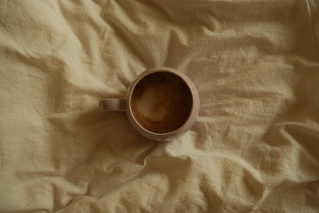 Aerial view of a coffee mug with frothy drink resting on a soft beige fabric, creating a warm and cozy ambiance.